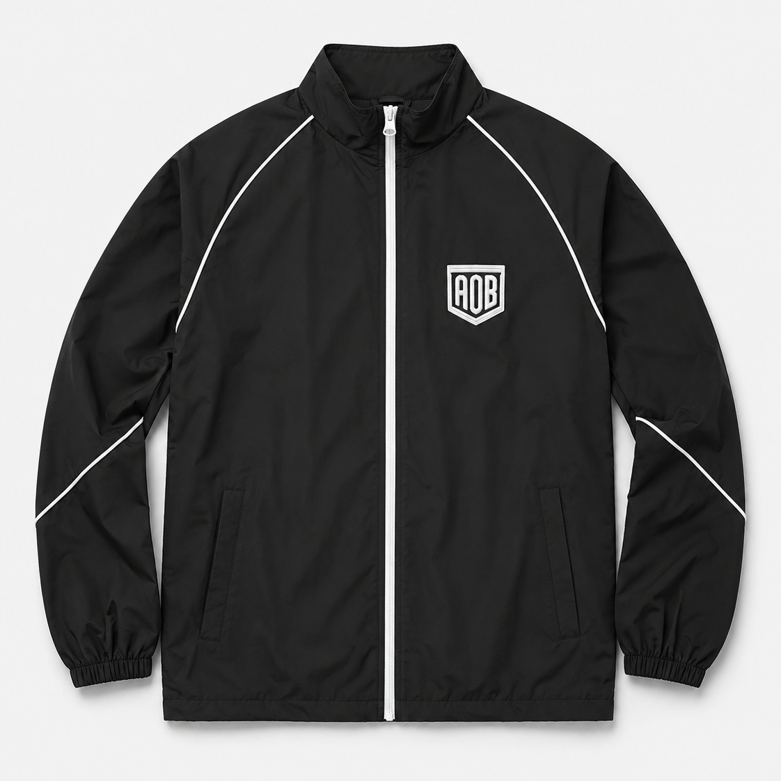 A black zip-up windbreaker jacket with white piping details and a white shield logo on the left chest, displayed on a light gray background.