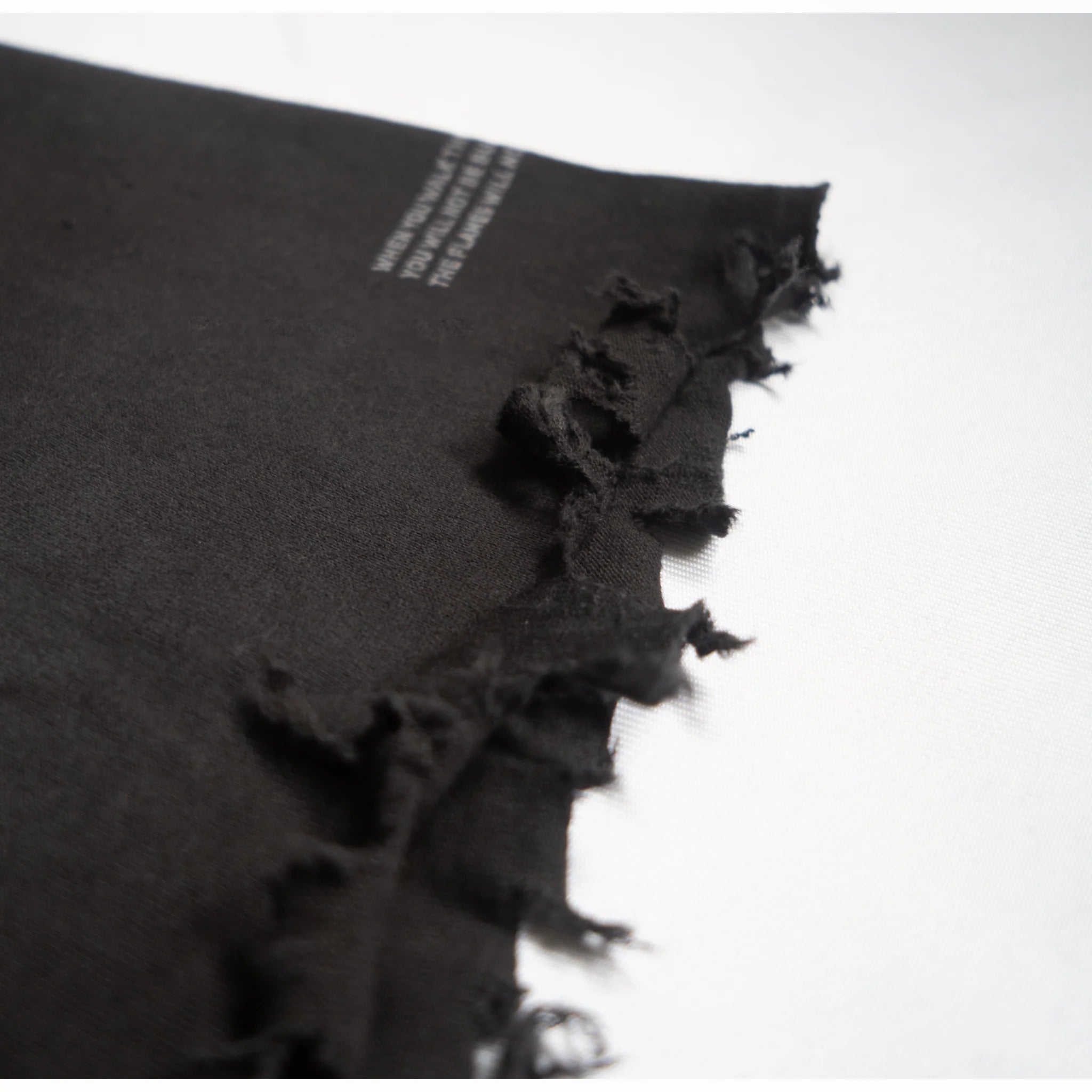 Black fabric with frayed edges on a white background